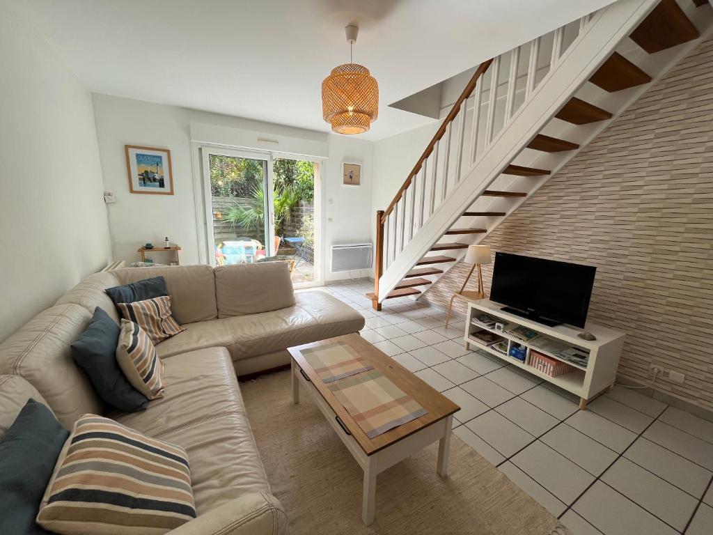 un salon avec un canapé et une télévision dans l'établissement Maison calme avec terrasse - Calypso, à Ouistreham