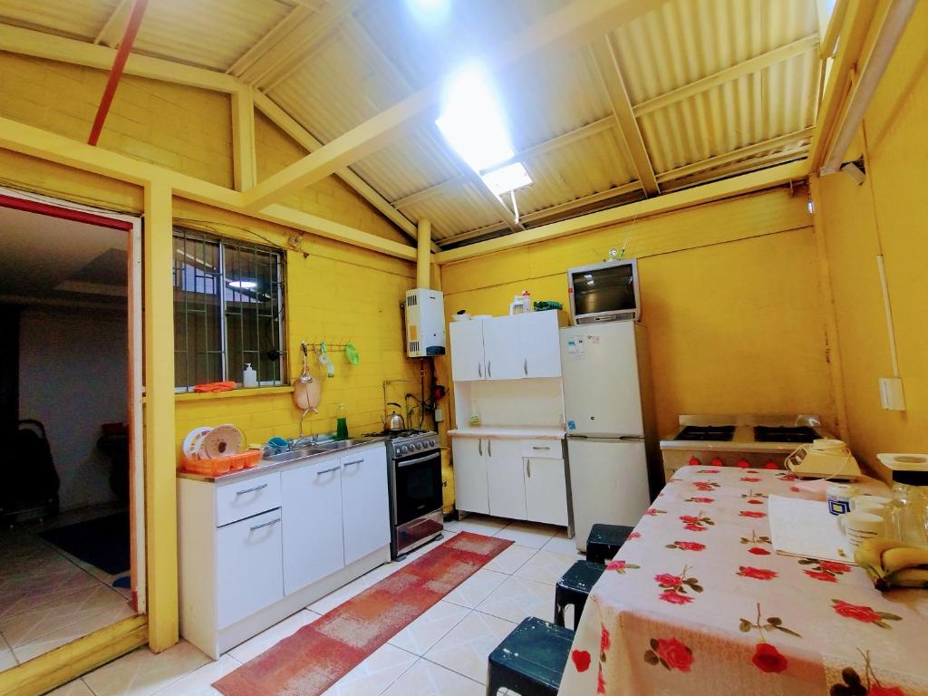 a kitchen with white appliances and yellow walls at Backpackers House - Near The Airport in Santiago