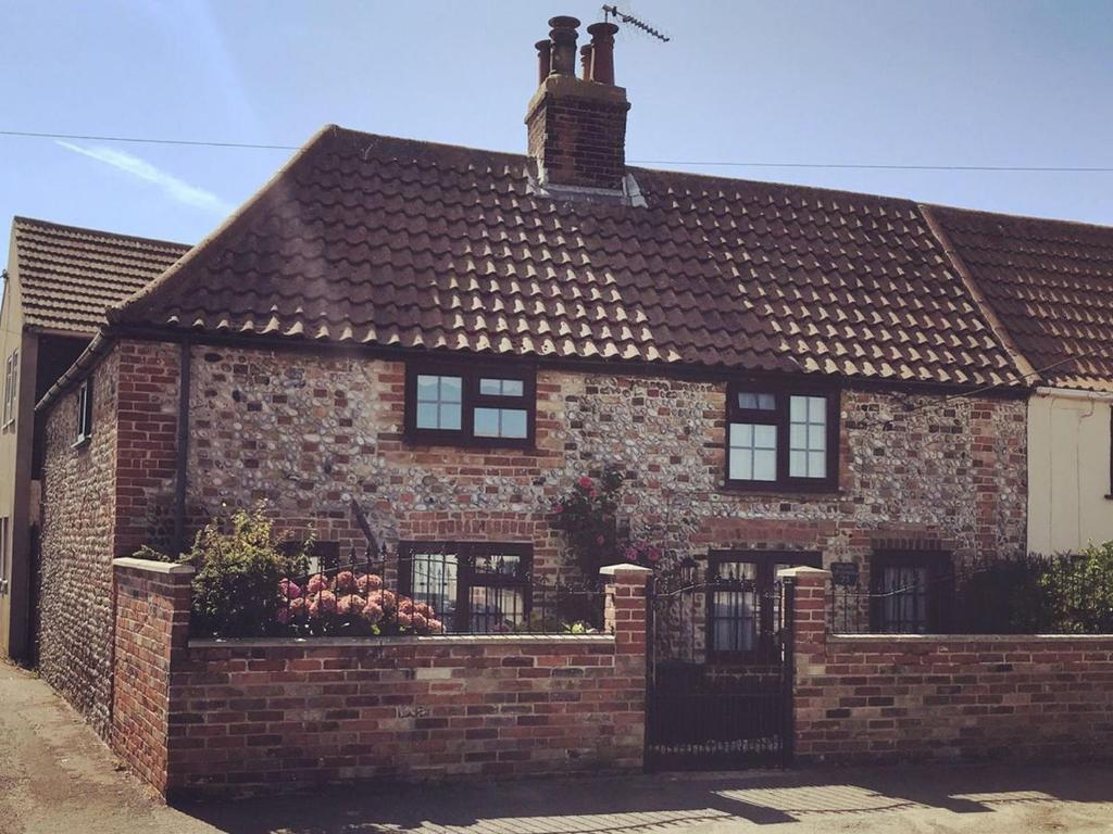 an old brick house with a brick wall at Whitestones Cottage in Caister-on-Sea