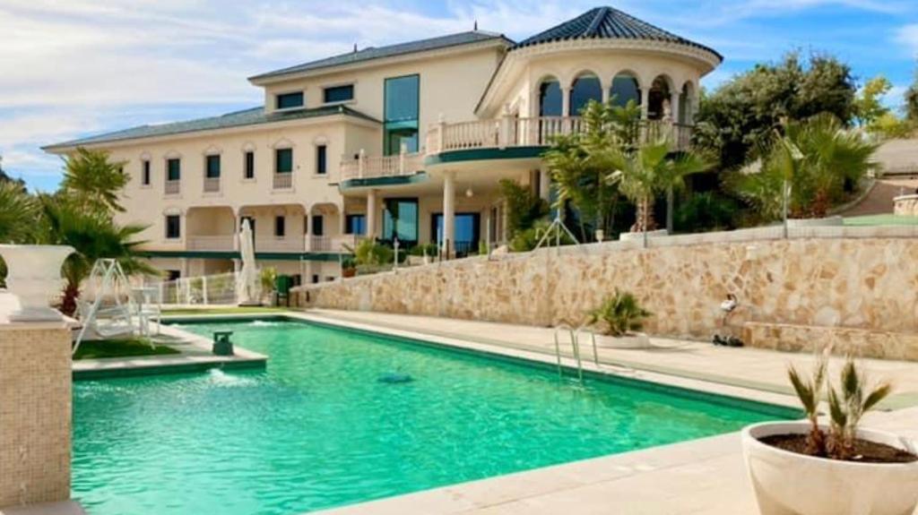 una casa grande con piscina frente a una casa en La Casa del Tejado Verde Toledo, en Toledo