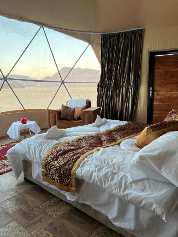 a bedroom with a large bed with a large window at Warm bubbles Wadi Rum in Wadi Rum