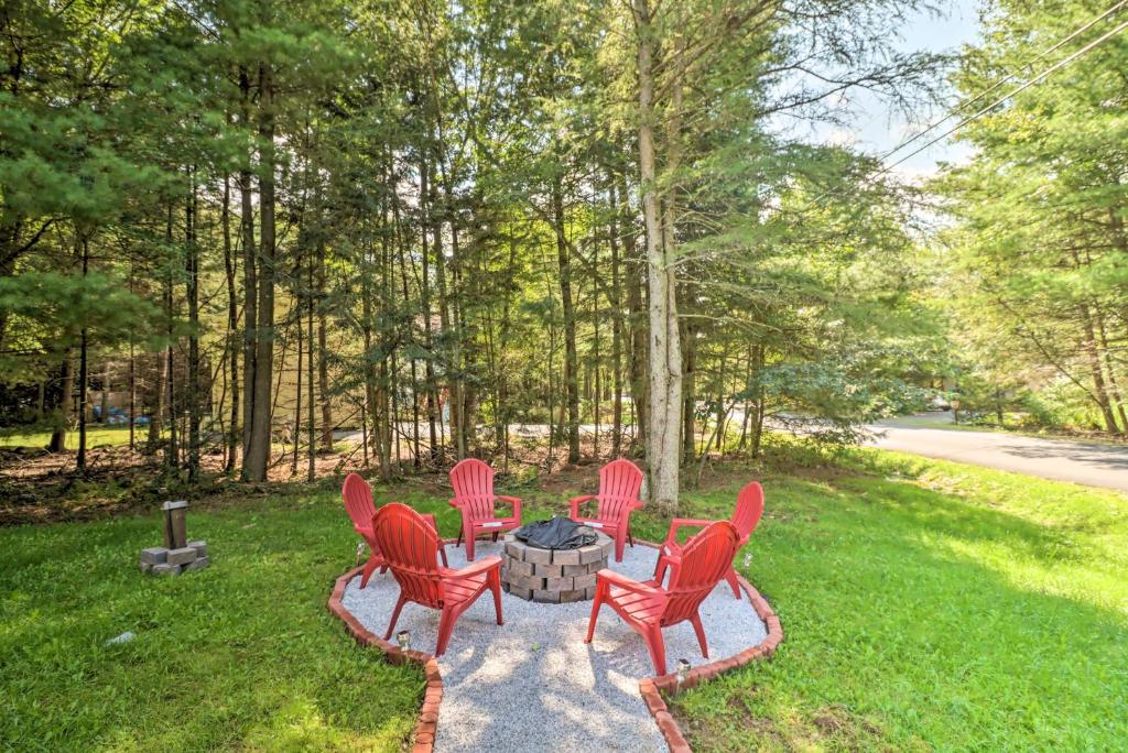 a group of red chairs sitting around a fire pit at Gorgeous Pocono Summit Retreat with Game Room! in Pocono Summit