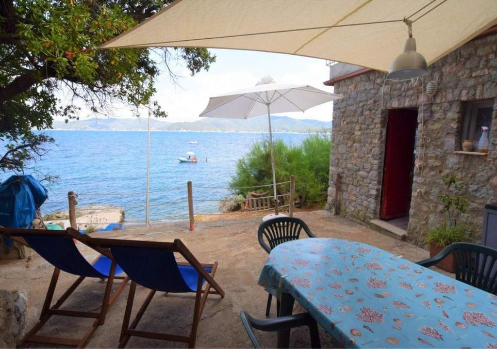 a patio with a table and chairs and an umbrella at Cotetonda - Appartamento Ilvia in Marciana Marina