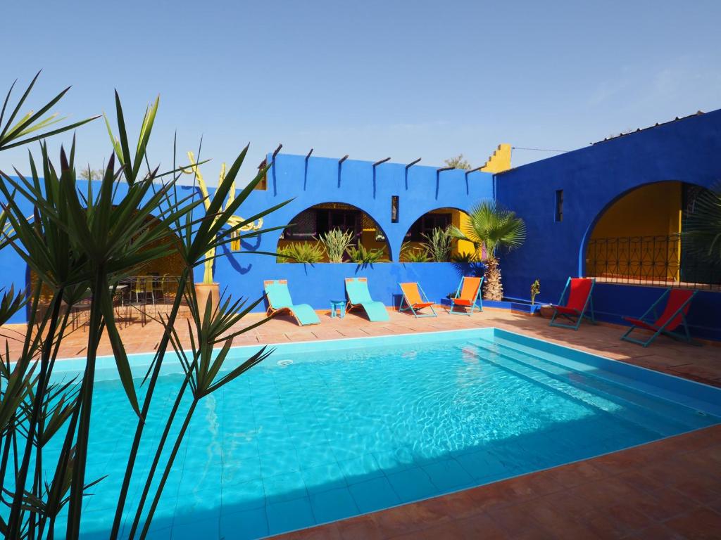 een blauw huis met een zwembad en stoelen bij La Kasbah du Paradis in Aksri