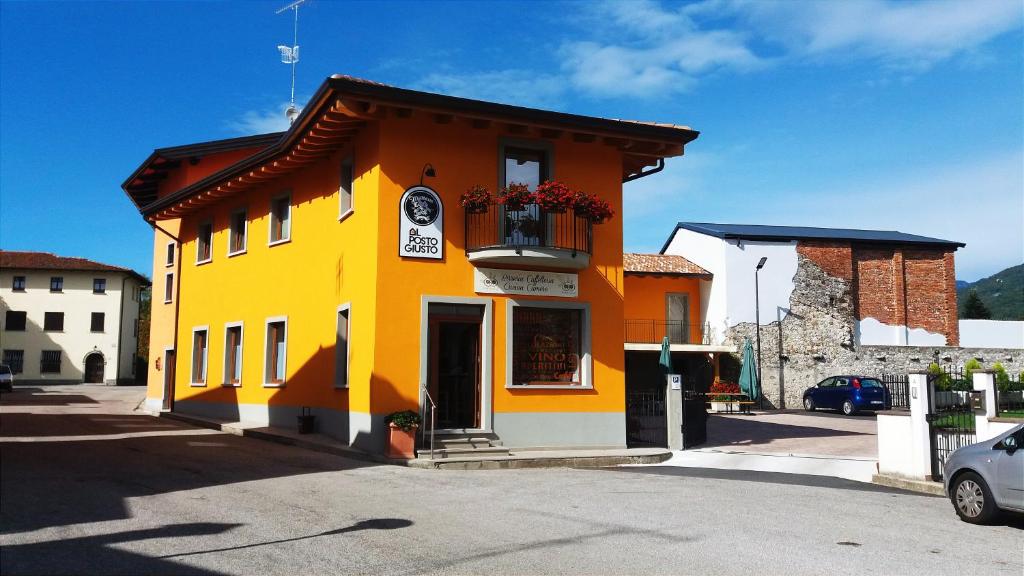 Edificio amarillo y naranja con balcón en Al Posto Giusto, en Nimis