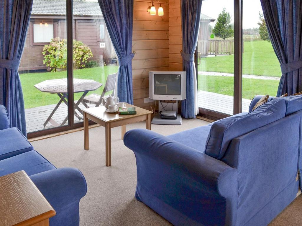 a living room with two blue chairs and a television at The Retreat in Woolfardisworthy