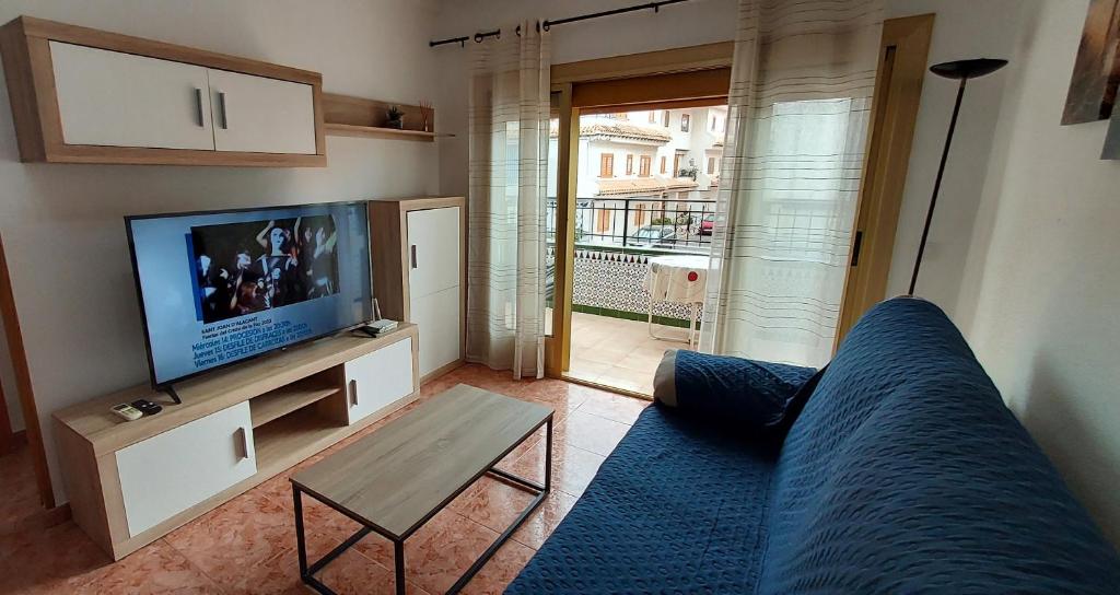 uma sala de estar com um sofá azul e uma televisão em Apartamento Urb Paraíso em Santa Pola