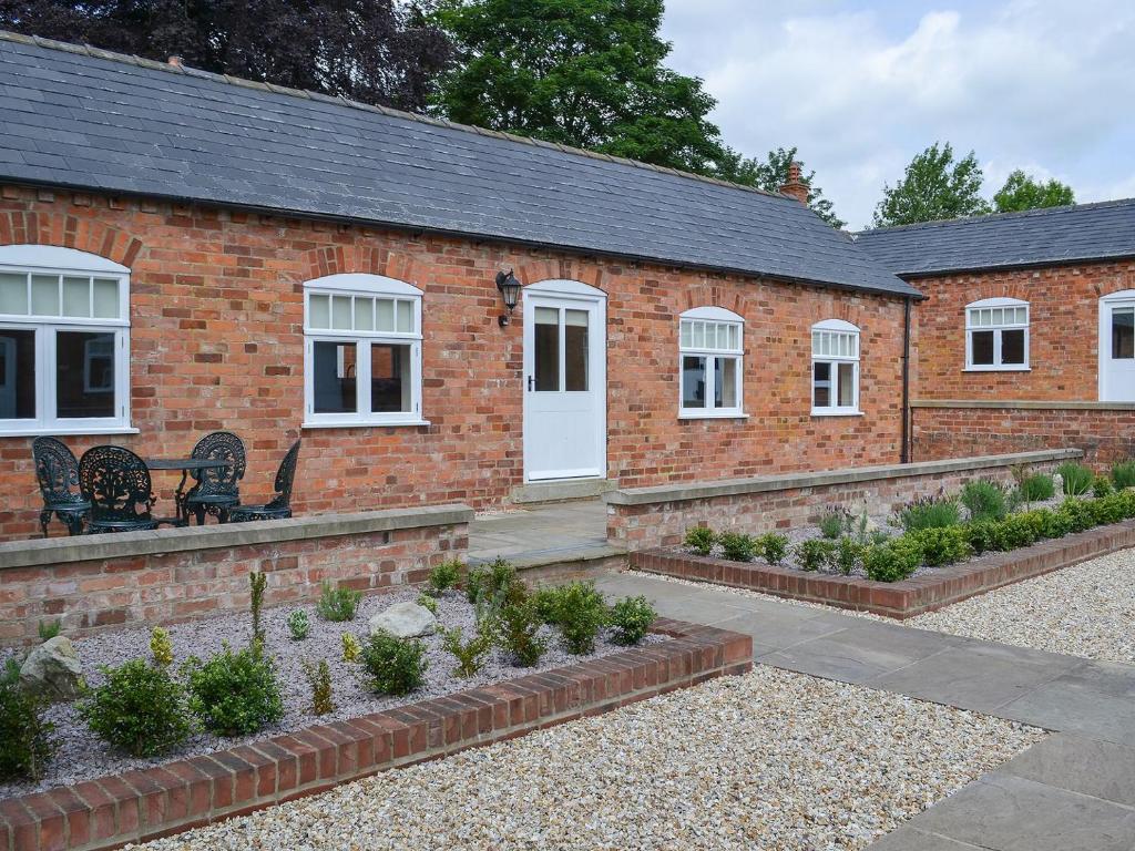 a brick building with white windows and a garden at Mays Mews in binbrook