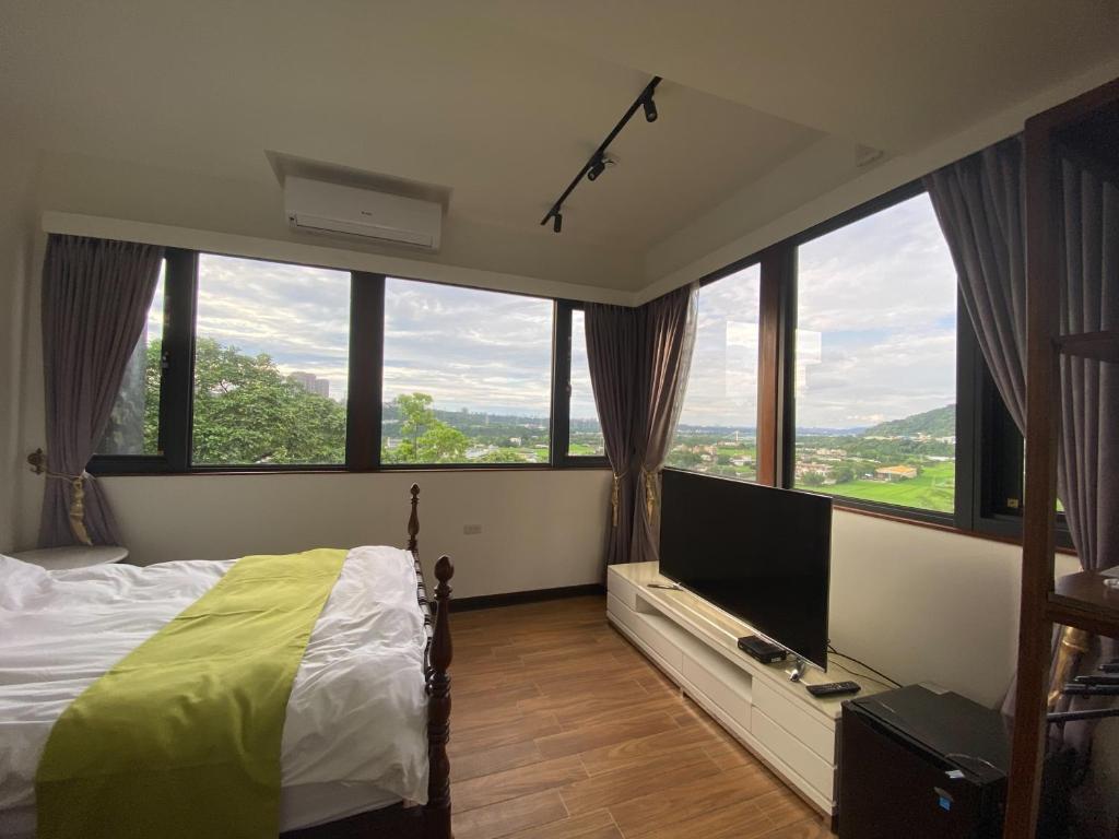Schlafzimmer mit großen Fenstern, einem Bett und einem TV in der Unterkunft Lemuju B&B Hotel in Daxi