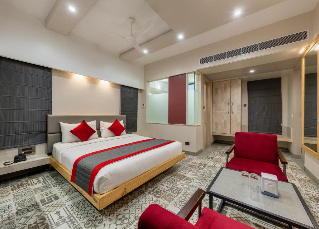 a bedroom with a large bed and red chairs at Pai Resort in Belgaum