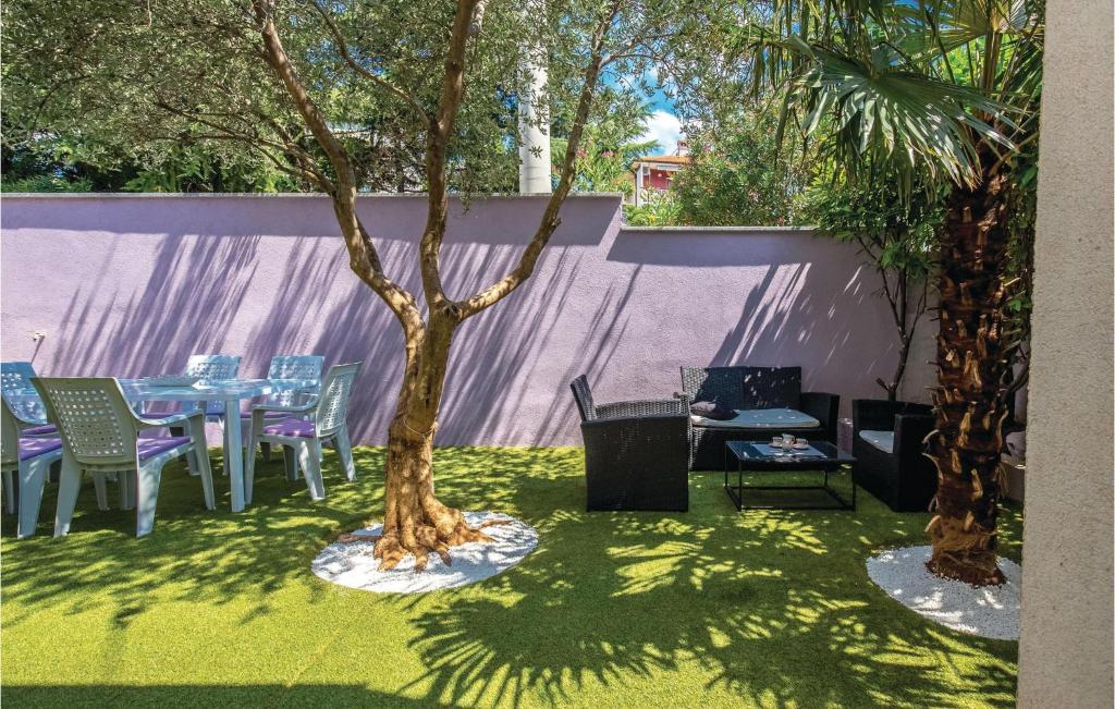 a patio with a table and chairs and a tree at Stunning Apartment In Kostrena With Kitchen in Kostrena
