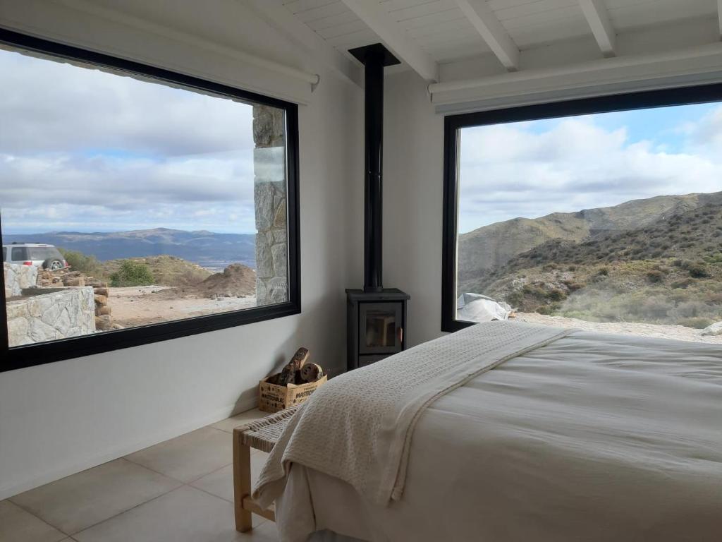 a bedroom with a bed and two large windows at Loft en Rincon de la Cumbre in La Cumbre