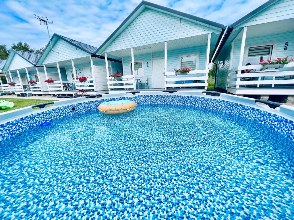 a swimming pool with a ball in front of a house at Domki Kapitana in Bobolin