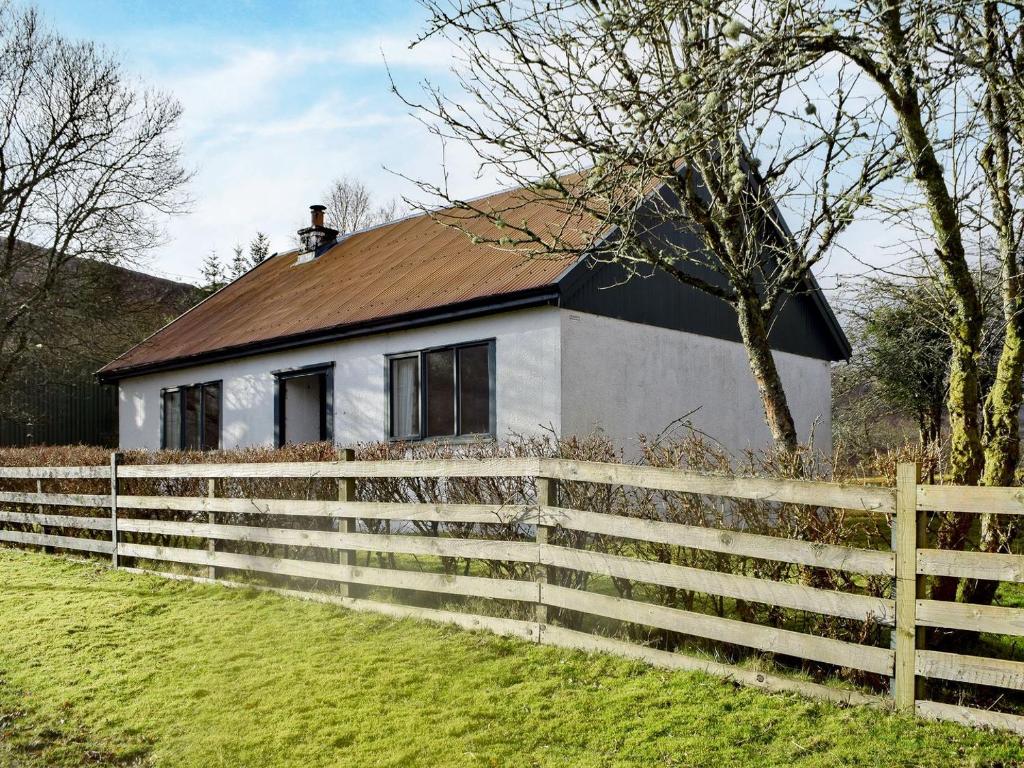 a white house with a fence in front of it at Ardura Cottage in Lochdon