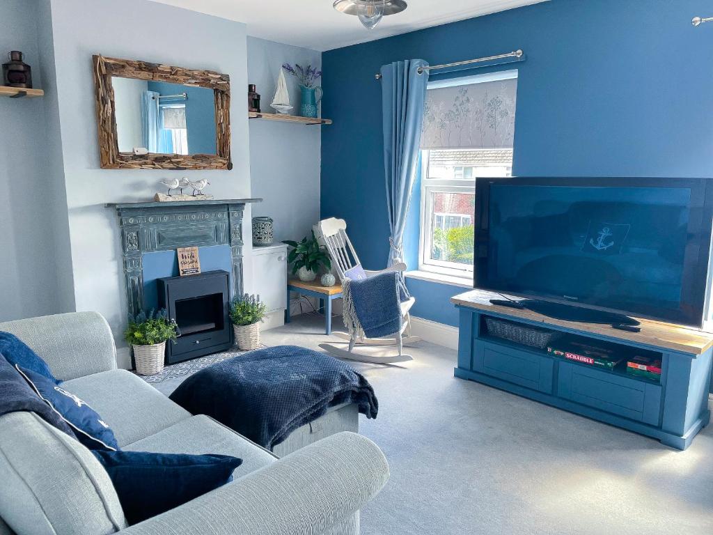 a living room with a tv and a blue wall at Sanderlings - Suffolk Coastal Escapes in Pakefield