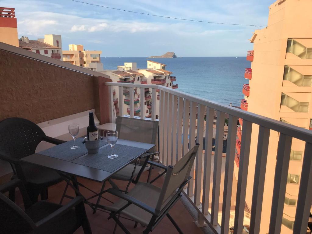 una mesa con copas de vino en un balcón con vistas al océano en Apartamento Vistamar, en La Manga del Mar Menor