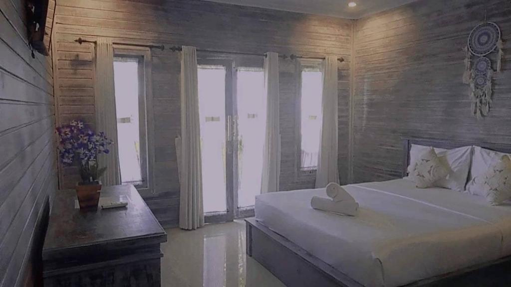 - une chambre avec un grand lit blanc et des fenêtres dans l'établissement Sarinah Beach - Bistro & Bungalow, à Nusa Penida