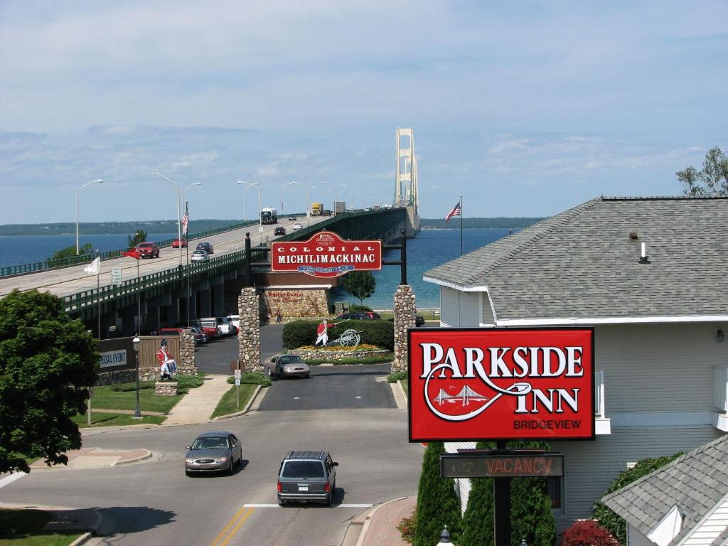 una señal para una posada Parkridge con un puente en el fondo en Parkside Inn Bridgeview, en Mackinaw City