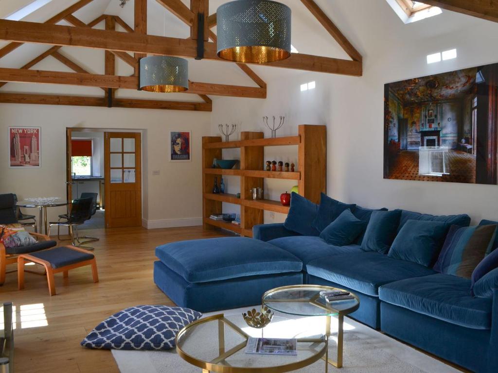 un soggiorno con divano blu e tavolo di The Stables a Berwick Hill