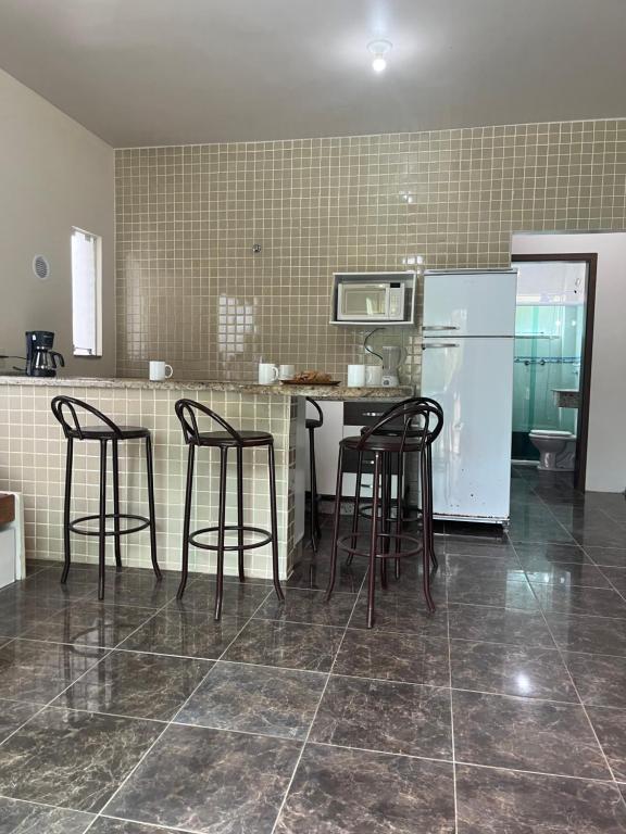 a kitchen with chairs and a counter with a refrigerator at La Lola Residencial in Bombinhas