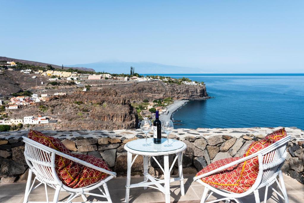 2 Stühle und ein Tisch mit einer Flasche Wein in der Unterkunft Casa Los Mangos - Increíbles vistas in Playa de Santiago