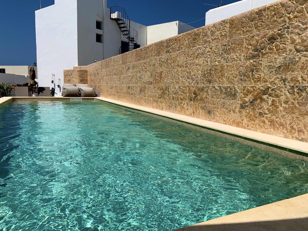 einen Pool vor einer Backsteinmauer in der Unterkunft Christina Hotel, Adults Only, Heated Salt Water Pool in Naoussa