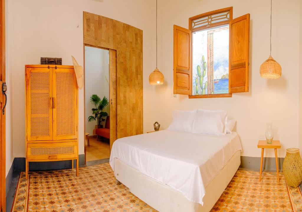 1 dormitorio con cama blanca y ventana en Casa Rosa - Alma Hotels, en Santa Marta