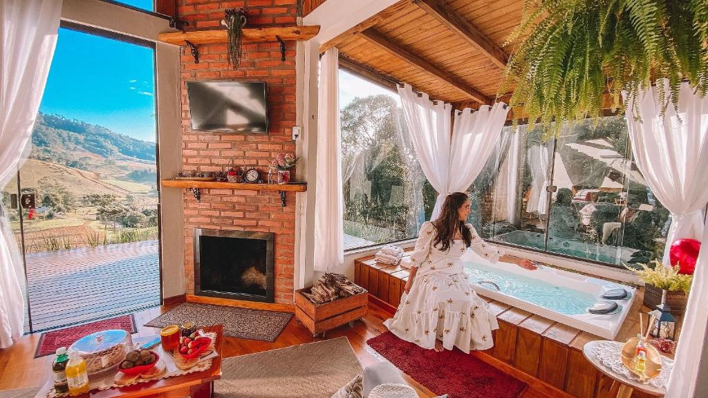 a woman standing in a bath tub in a room with a fireplace at Chalé Caminho do Sol in Rancho Queimado