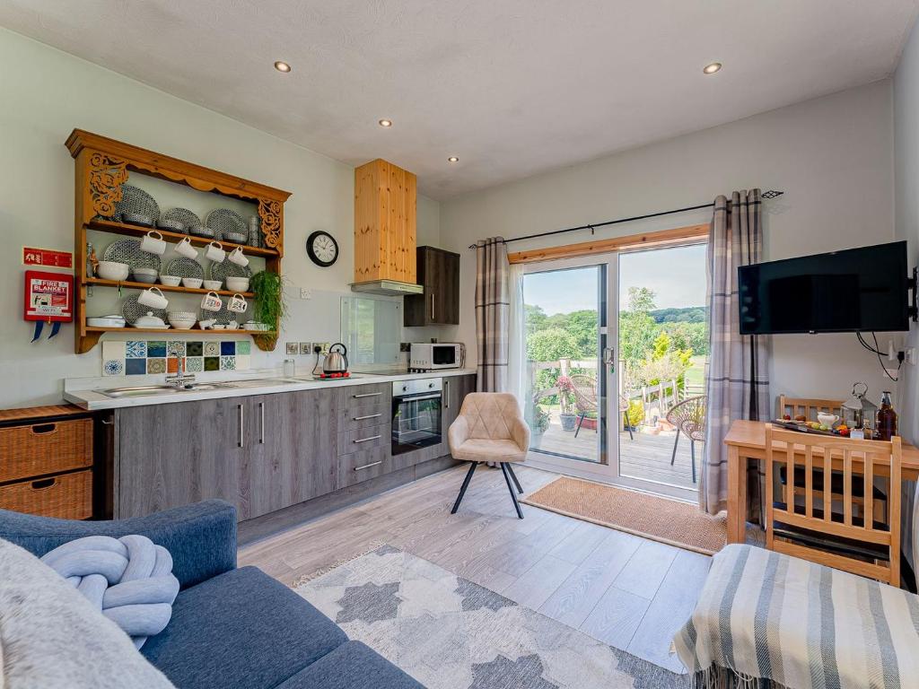 a living room with a blue couch and a kitchen at Cwtch Enrico - Uk39064 in Scyborycoed