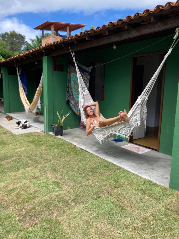 a woman laying on a hammock outside a house at Caju com Mel in Moreré