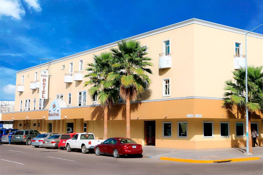un grand bâtiment avec des voitures garées devant lui dans l'établissement Hotel Fenix, à Los Mochis