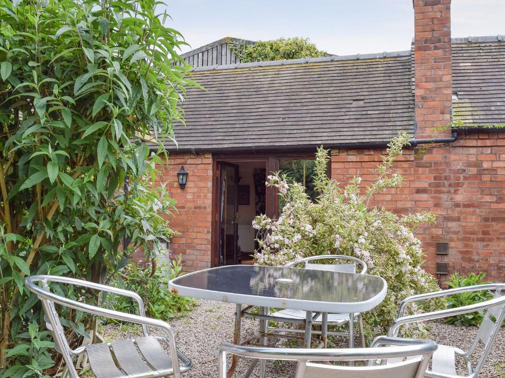 a patio with a table and chairs in a garden at The Cotes in Malvern Wells