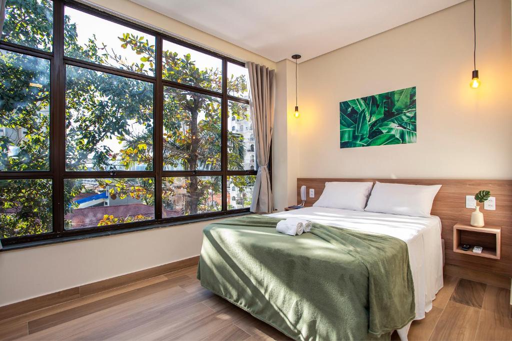 a bedroom with a bed and large windows at GoÁtica Aeroporto Congonhas in Sao Paulo