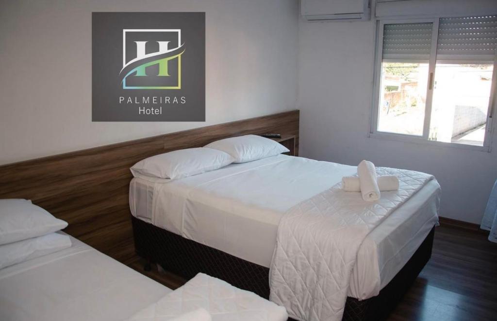 Habitación de hotel con 2 camas con sábanas blancas en Hotel Palmeiras en Santana do Livramento