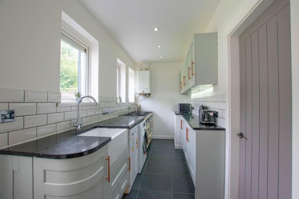 a kitchen with white cabinets and black counter tops at Sophisticated Home with Beautiful & Large Garden in Cardiff