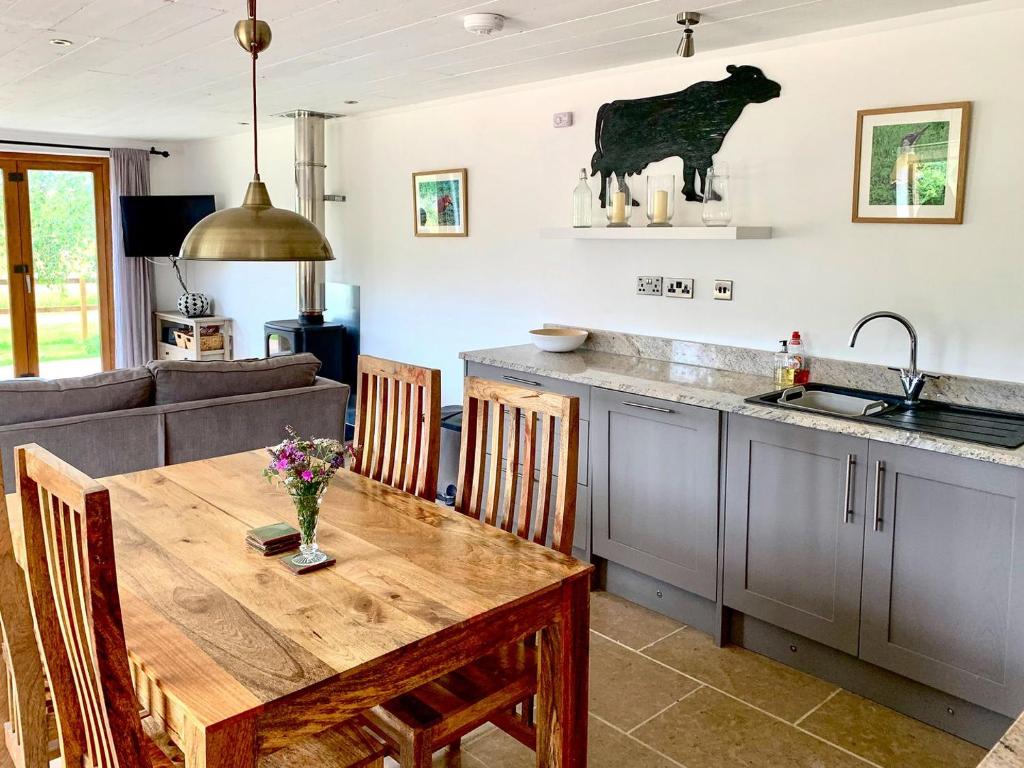 a kitchen with a wooden table and a kitchen with a cow on the wall at The Milking Parlour in Keevil
