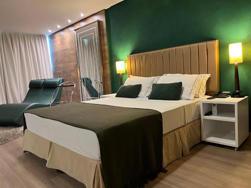 a bedroom with a large bed and a green wall at Alfa Hotel in Viçosa