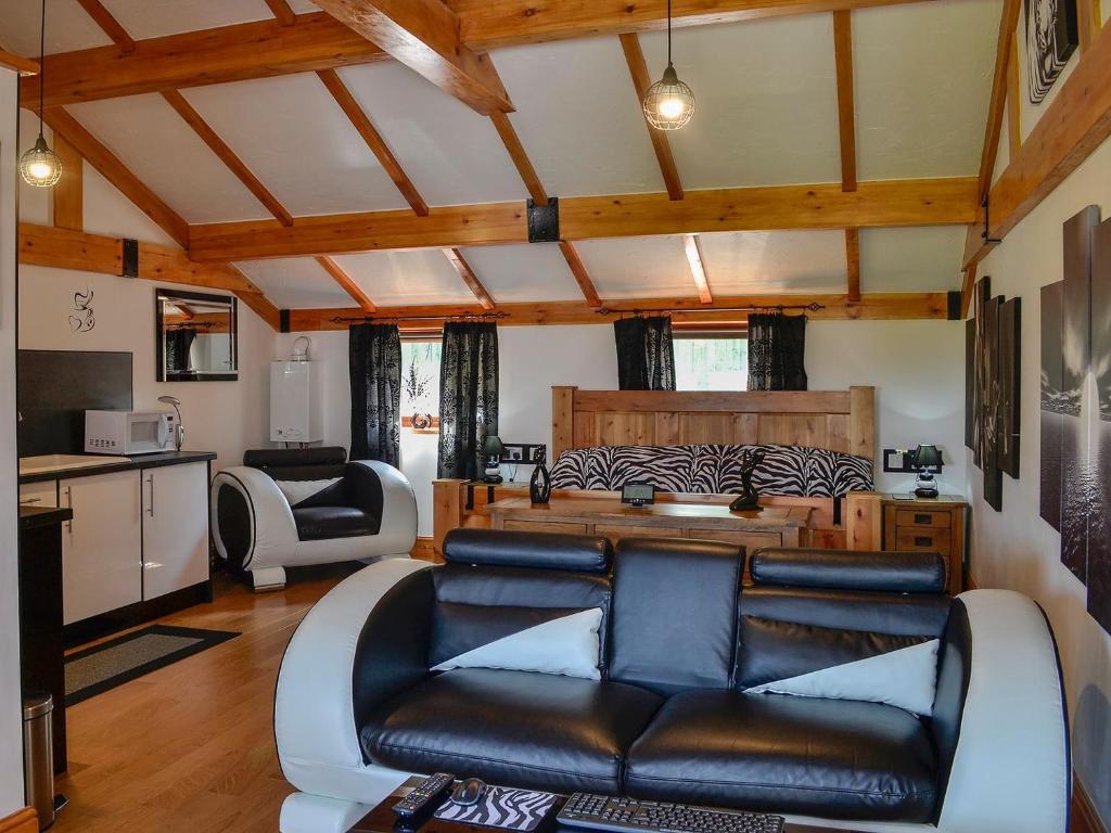 a living room with a leather couch and a kitchen at Swallow Cottage - Ukc3427 in Dalston
