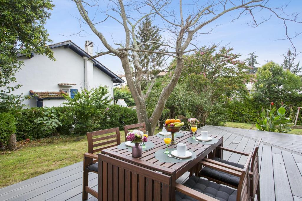 einen Holztisch und Stühle auf einer Holzterrasse in der Unterkunft Beautiful house with a large yard at the heart of Hendaye - Welkeys in Hendaye