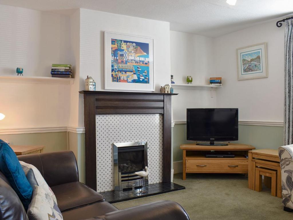 a living room with a fireplace and a television at Old Town Cottage in Sidmouth
