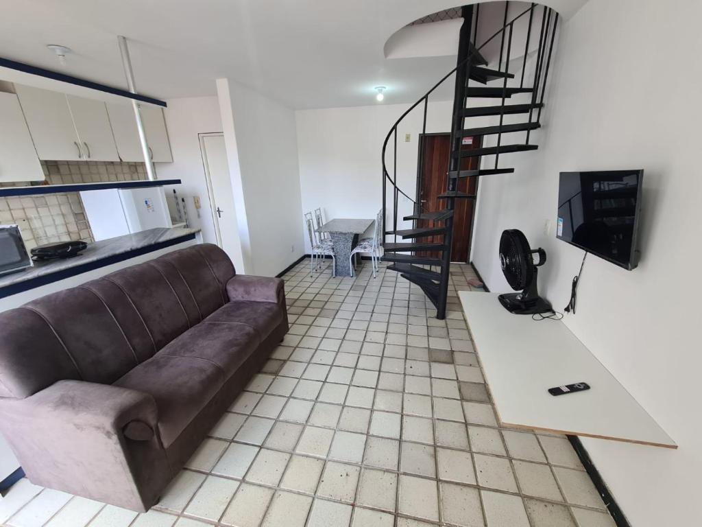 een woonkamer met een bank en een wenteltrap bij Duplex Beira Mar Pajuçara Maceió in Maceió