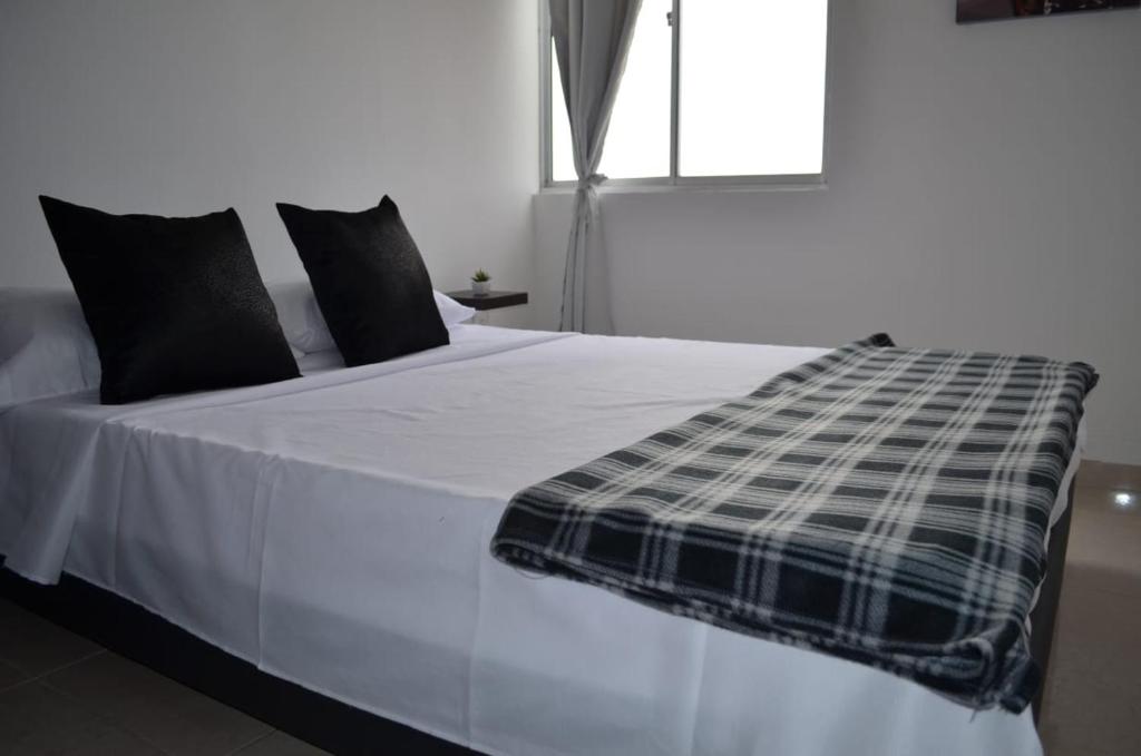 a bed with a black and white blanket on it at Vacaciona a 3 minutos del Parque del Cafe in Armenia