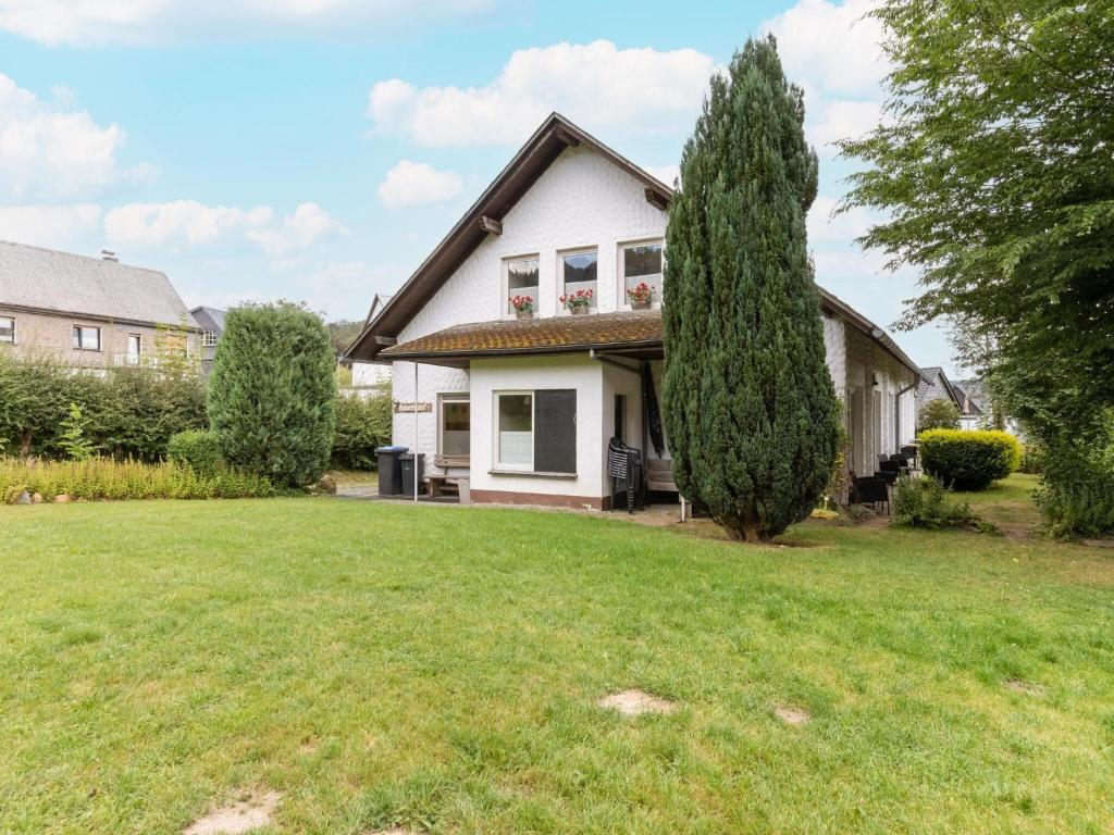 a white house with a tree in the yard at Cosy holiday home with terrace in Winterberg in Winterberg