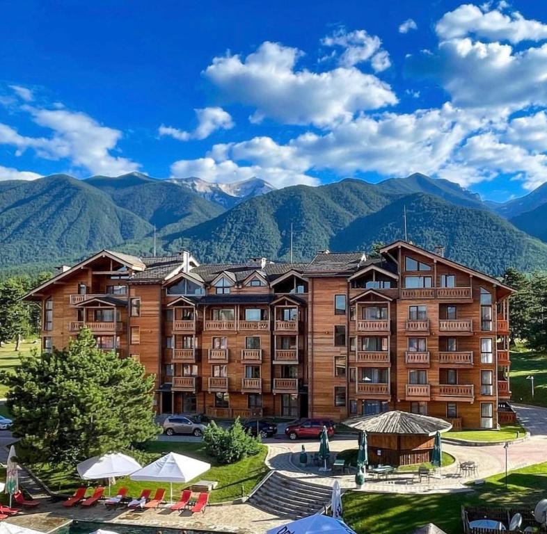 a large building with mountains in the background at Allure in Pirin Golf & Country Club in Razlog