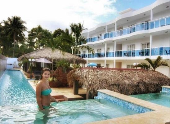 a woman in a swimming pool next to a hotel at El Cabarete Boutique Hotel in Cabarete