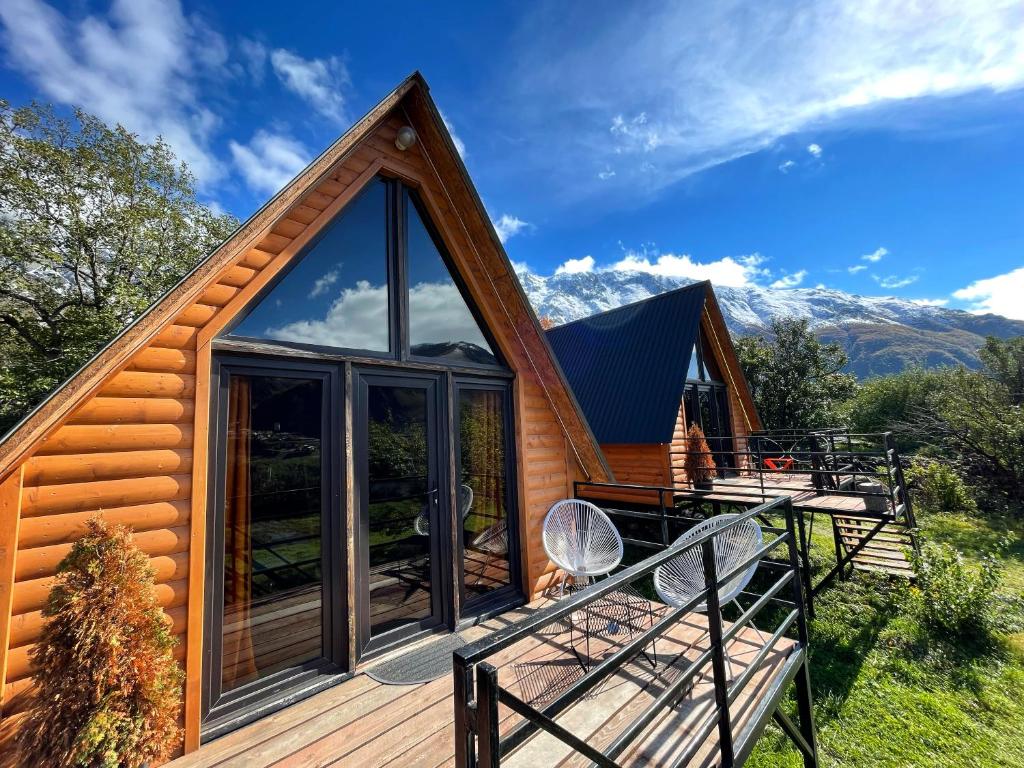 a log cabin with a large glass window and a deck at Kazbegi Kuro Cottages in Kazbegi