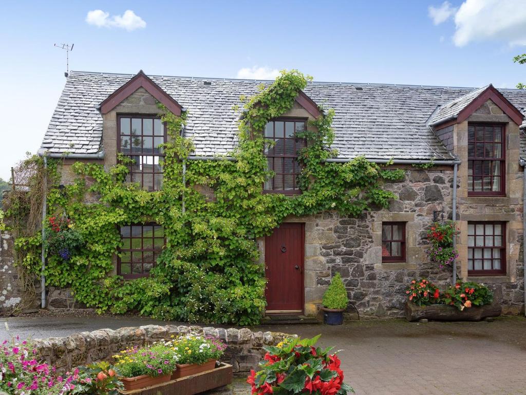 an old stone house with a red door at Fochy Cottage in Milnathort