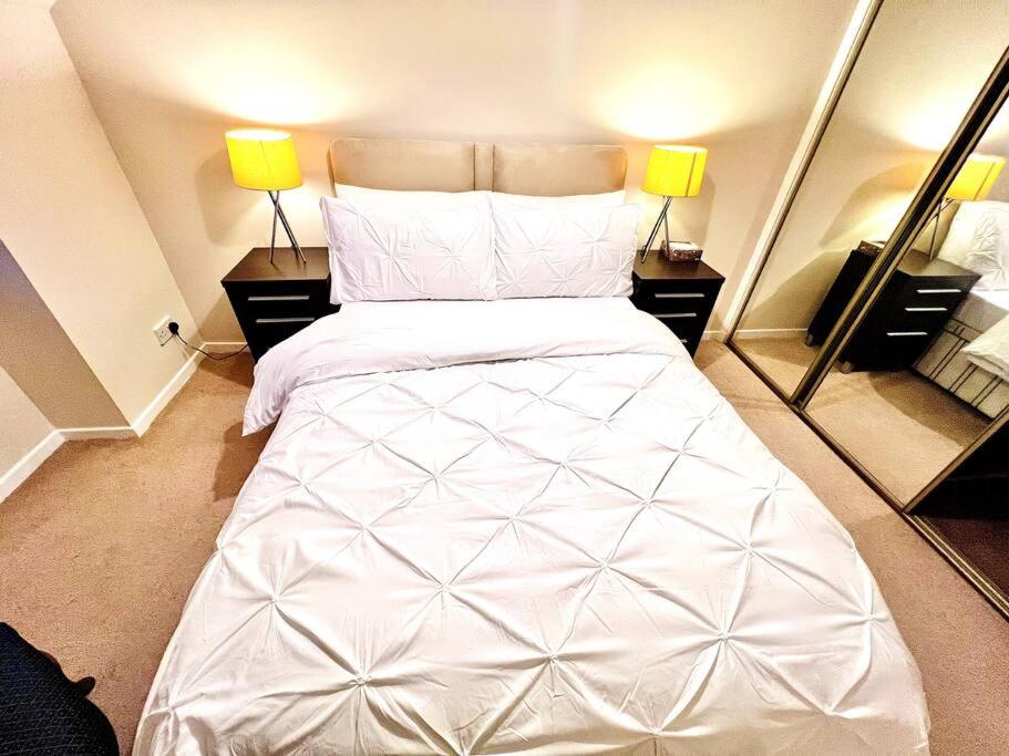a bedroom with a large white bed with two mirrors at Stylish North Spring Exec One Bedroom Apartment in Aberdeen