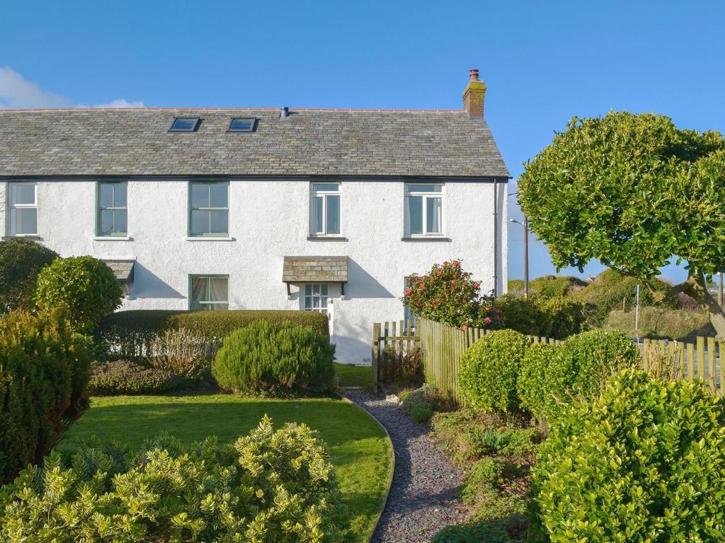 uma casa branca com uma cerca e um jardim em Tregatta Terrace em Tintagel