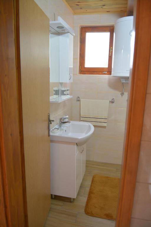 uma casa de banho com um lavatório branco e uma janela em Dobar pogled em Bajina Bašta